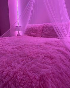 a bed with a pink comforter and mosquito netting over it's headboard