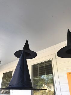 three black witches hats hanging from the ceiling