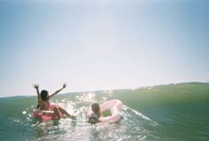 two people in the water on their stomachs and one is riding a boogie board