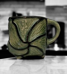 a green coffee cup sitting on top of a counter