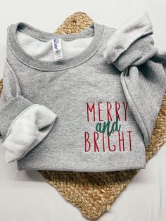 a gray shirt with merry and bright on it sitting on top of a woven mat