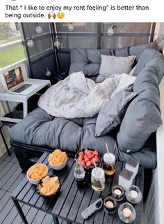 a bed sitting on top of a wooden floor next to a table filled with food