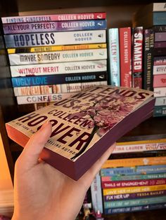 a person holding up a book in front of a bunch of books