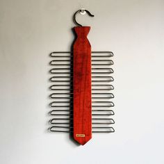 a wooden comb hanging on the side of a wall with a metal hanger attached to it