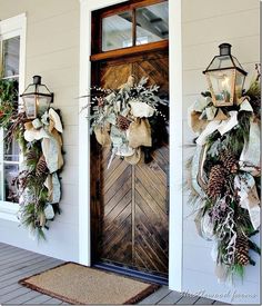 two christmas wreaths on the front door of a house with pine cones and other holiday decorations