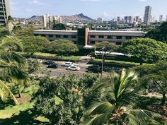 an aerial view of a parking lot with cars parked on the street and buildings in the background