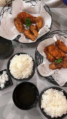 several different types of food in black bowls on a white counter top with rice and sauces