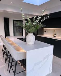 a vase with flowers sitting on top of a kitchen counter next to bar stools