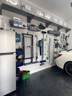 a white car parked in front of a garage with lots of tools on the wall