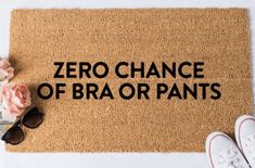 a door mat that says,'zero chance of bra or pants'next to sunglasses and flowers