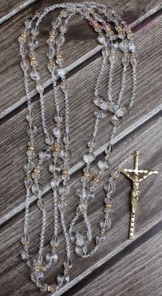 a rosary with a cross on it sitting on top of a wooden table next to a necklace