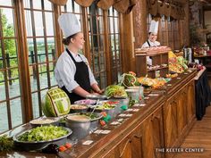 a woman standing in front of a buffet line filled with lots of vegetables and fruit