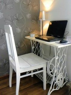 a laptop computer sitting on top of a white desk next to a chair and lamp