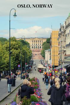 people are walking down the street with flowers in front of them and an old building on the other side