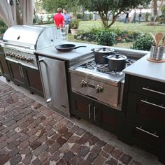 an outdoor kitchen with pots and pans on the burner, oven and grill