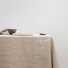 a table topped with a white cloth and two black bowls sitting on top of it