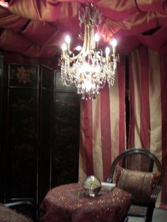 a chandelier hanging from the ceiling in a room with red and white curtains