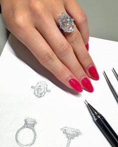 a woman's hand with red nail polish and diamond ring on top of a piece of paper