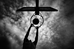 a man is holding up a basketball hoop in the air with his hands and feet