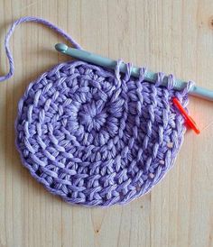 a crochet potholder with two knitting needles on it and yarn in the middle