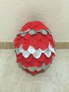 a red and silver ball sitting on top of a tile floor next to a wall