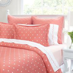 a bed with pink and white polka dot comforter set on top of it in front of a window