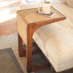 a table with a cup on top of it in front of a couch and rug