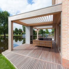 a wooden deck next to a lake with a couch on it and trees in the background