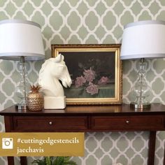 a table with two lamps and a painting on the wall in front of it next to a potted plant