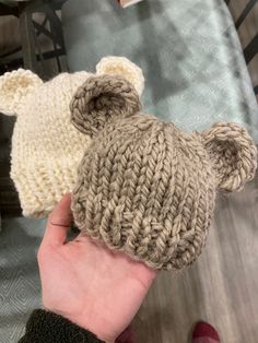 a hand is holding two knitted teddy bears