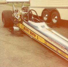 a race car sitting on the ground next to a trailer