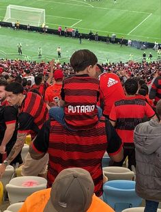 a group of people in red and black shirts standing on top of a soccer field