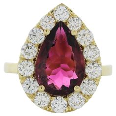 The fashion ring features a 3.75-carat pear-cut rubellite gemstone set in 18 karat yellow gold, accented by 14 round-cut diamonds with a total weight of 1.7 carats. The combination of the vibrant rubellite and sparkling diamonds against the yellow gold setting is likely to create a bold and elegant statement piece, suitable for enhancing various fashion looks and occasions. Pear-shaped Yellow Gold Ruby Ring, Pear-shaped Ruby Ring With Halo Setting, Dopamine Dressing, Pear Ring, Ruby Diamond Rings, Yellow Gold Setting, Fashion Ring, Ruby Diamond, Sparkle Diamonds