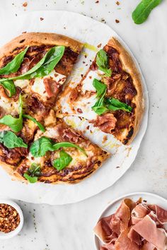 a pizza sitting on top of a white plate covered in cheese and spinach leaves