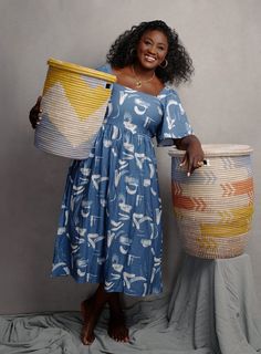 a woman in a blue dress is holding two large baskets and smiling at the camera