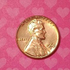 an image of a penny with hearts on the side and pink paper in the background