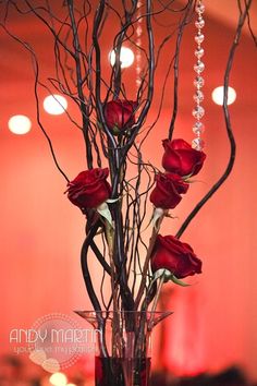 a vase filled with red roses sitting on top of a table next to a chandelier