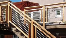 an umbrella sitting on top of a wooden deck next to a building with doors and windows