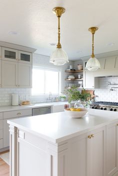 a white kitchen with two hanging lights over the island