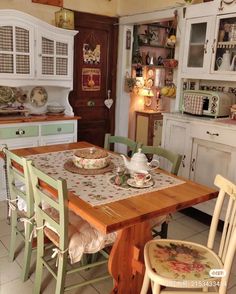 a kitchen with white cabinets and wooden table in it's centerpiece, surrounded by green chairs