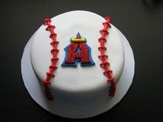 a baseball cake with red and blue icing on it's side, sitting on top of a black table