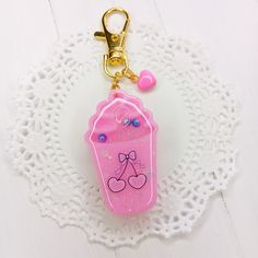 a keychain with a pink cup on it sitting on top of a doily