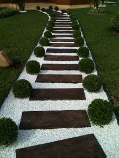 a garden path made out of wood and white gravel with grass growing on the sides