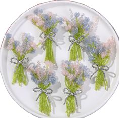 small flowers are placed on a plate with beaded ribbon around the stems and leaves