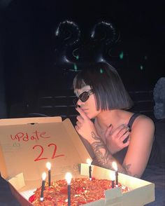 a woman laying on the ground next to a pizza box with candles burning in it