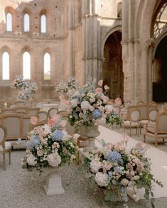 two vases filled with flowers sitting on top of a stone floor next to chairs