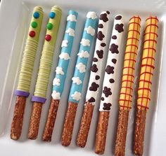 a white plate topped with lots of different types of candy sticks covered in icing