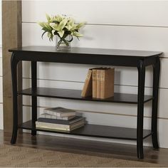 a black shelf with books and flowers on it