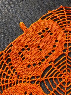 an orange crocheted doily on the ground