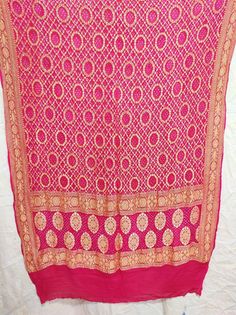 A beautifully Handwoven Pure BANARASI GEORGETTE BANDHANI DUPATTA with all over ZARI weave making it a Royal one Georgette is a light-weight, crinkled and sheer fabric, displaying an overall bouncy look. A strong absorbent, Georgette is easy to dye and has dull-rough texture. Pure Georgette is woven out of Silk yarns Banarasi is globally acclaimed for its rich use of zari (brocade)) and beautiful bandhani dyes.  Bandhani, also known as Bandhej; is a type of TIE DYE textile which is adorned by plu Luxury Bandhani Print Dupatta For Party, Luxury Bollywood Bandhani Print Dupatta, Traditional Wedding Scarves With Motifs, Wedding Scarves With Traditional Patterns For Festivals, Motif Scarves For Weddings And Festivals, Festive Scarves With Traditional Patterns And Drape, Wedding Scarves With Motifs For Festivals, Wedding And Festival Scarves With Motifs, Semi-stitched Bohemian Pink Saree